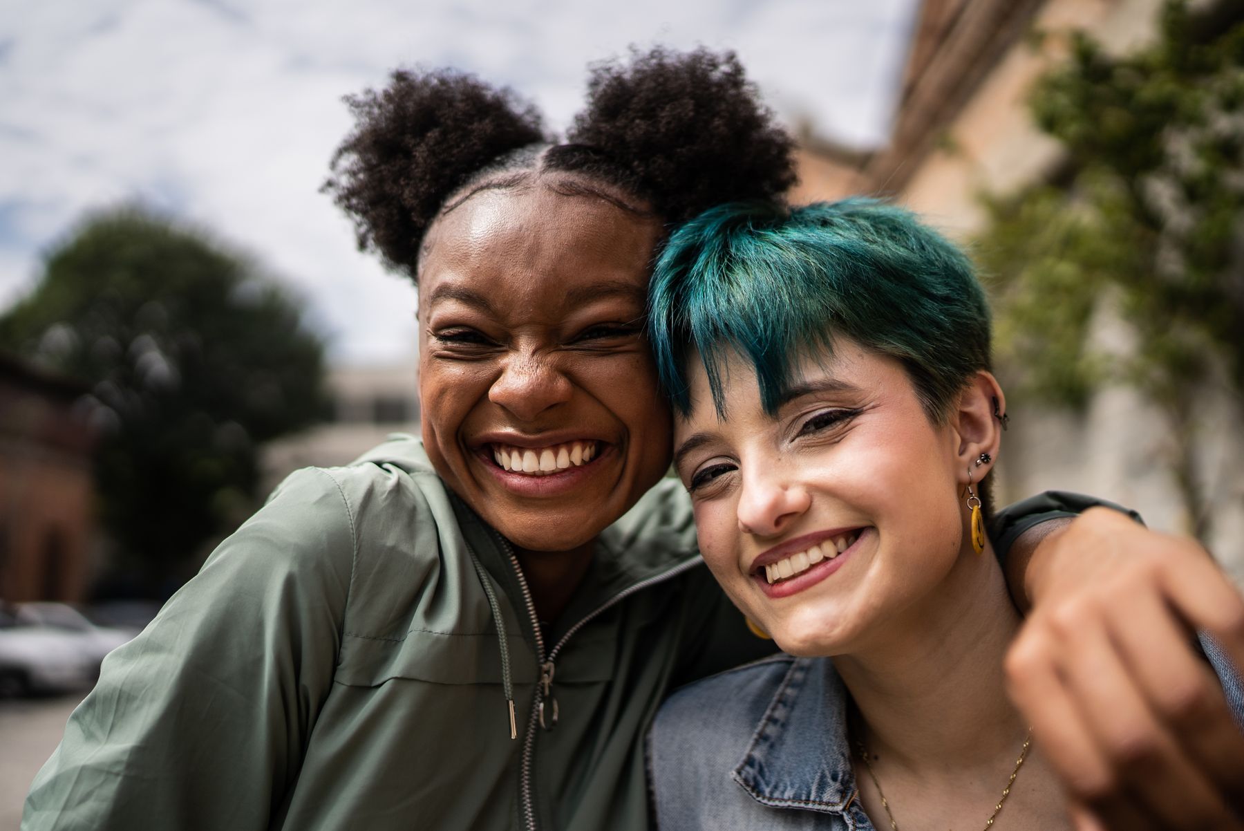 Two friends hugging and smiling outdoors